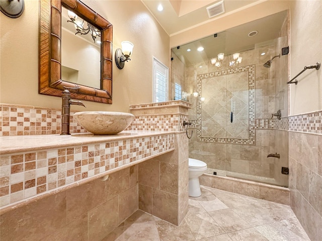 bathroom featuring toilet, a shower with shower door, sink, and tile walls