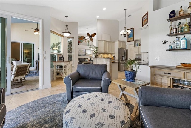 tiled living room with ceiling fan with notable chandelier and high vaulted ceiling