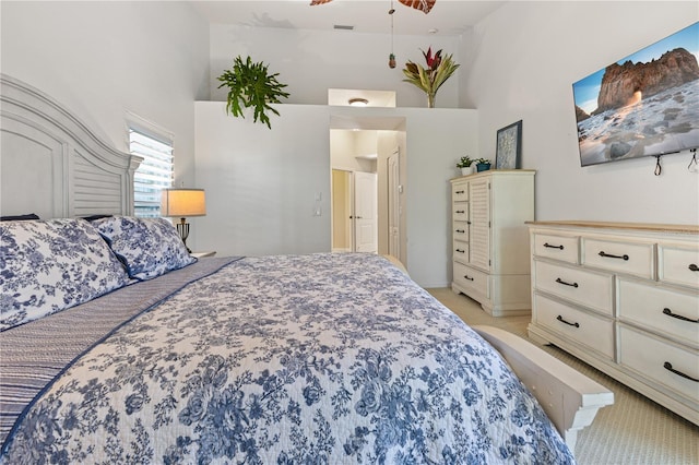 bedroom featuring a towering ceiling and light carpet