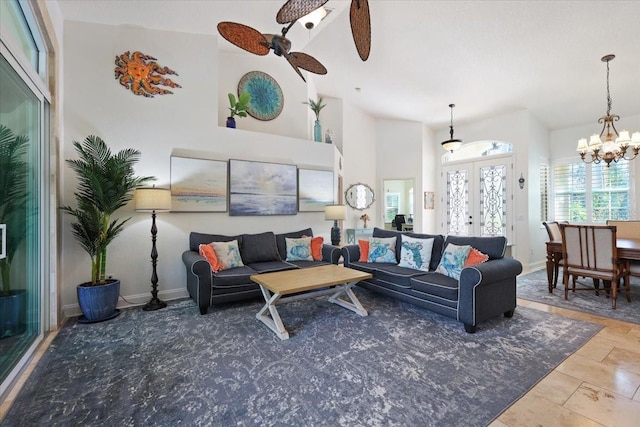 living room with french doors, a towering ceiling, and ceiling fan with notable chandelier