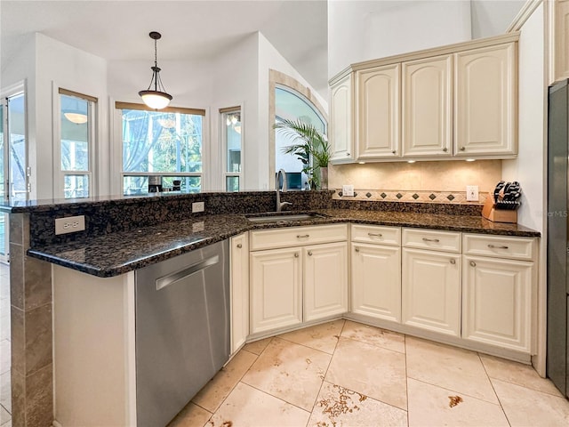 kitchen with hanging light fixtures, sink, stainless steel dishwasher, and dark stone counters