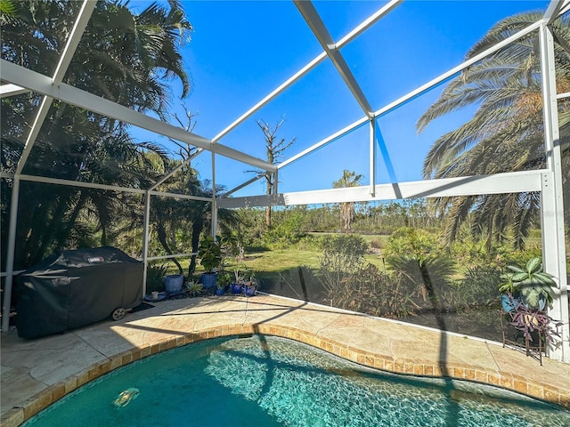 view of swimming pool with a grill, a patio area, and glass enclosure