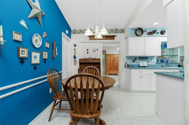 dining space with light tile patterned floors, an inviting chandelier, lofted ceiling, and sink