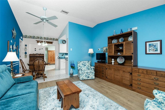 living room with ceiling fan with notable chandelier, light hardwood / wood-style floors, and lofted ceiling