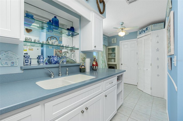 kitchen with ceiling fan, sink, white cabinets, and light tile patterned floors