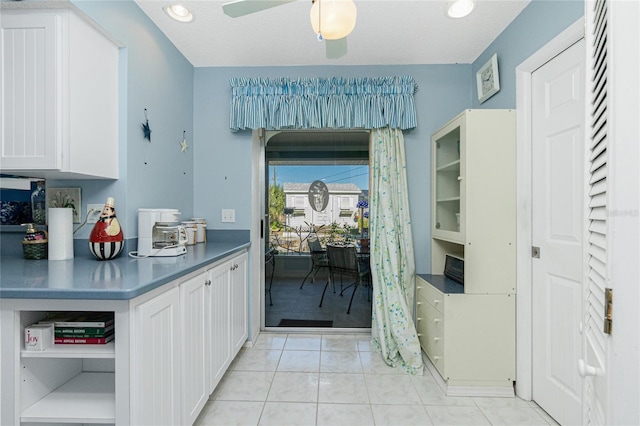 kitchen featuring white cabinets, light tile patterned floors, a textured ceiling, and ceiling fan