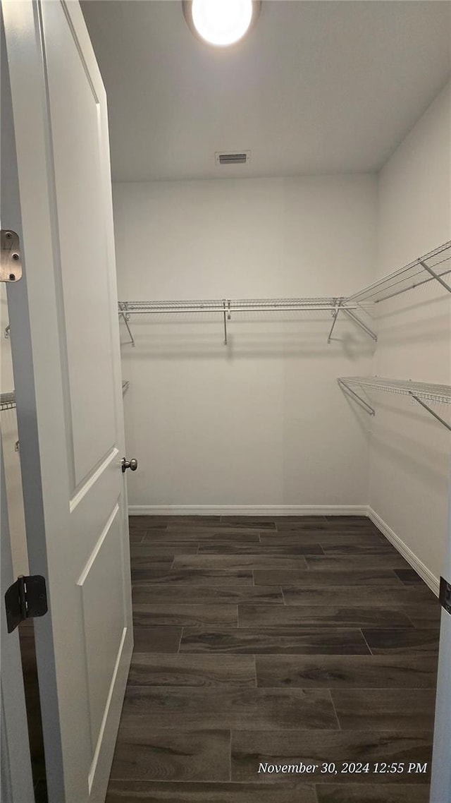 walk in closet with dark hardwood / wood-style flooring