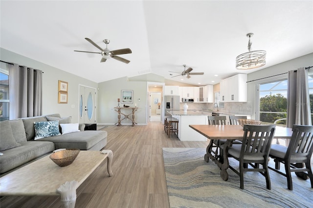 dining room featuring ceiling fan with notable chandelier, light hardwood / wood-style floors, lofted ceiling, and sink