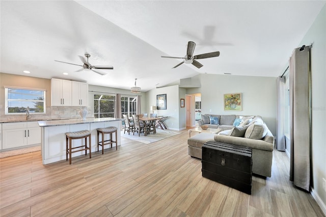 living room with a healthy amount of sunlight, lofted ceiling, and light wood-type flooring