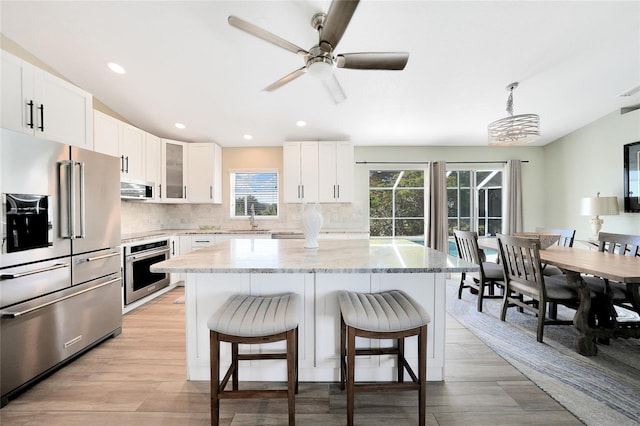 kitchen with pendant lighting, a center island, white cabinetry, and appliances with stainless steel finishes