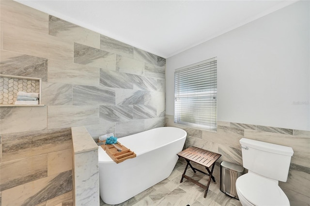 bathroom featuring a bathing tub, tile walls, and toilet