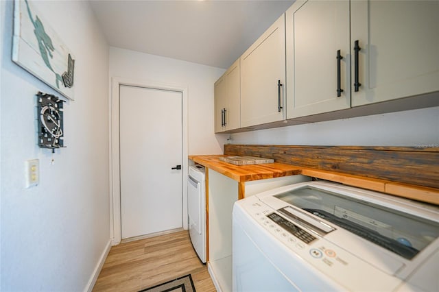 laundry room with washer and clothes dryer, light hardwood / wood-style flooring, and cabinets