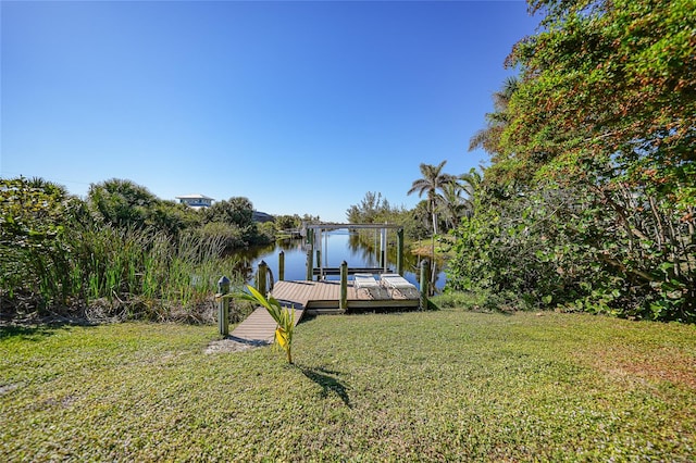 view of dock with a lawn and a water view