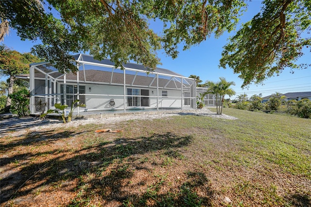 back of property with glass enclosure and a yard