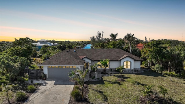 ranch-style house with a garage and a lawn