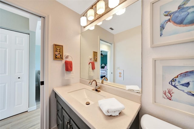 bathroom with hardwood / wood-style floors, vanity, and toilet