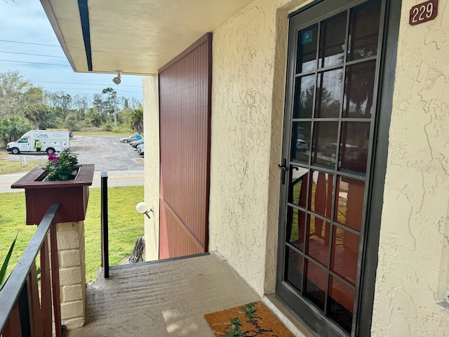 72 Boundary Blvd Unit 229, Rotonda West, FL 33947 - doorway to property with stucco siding, a porch, and a lawn