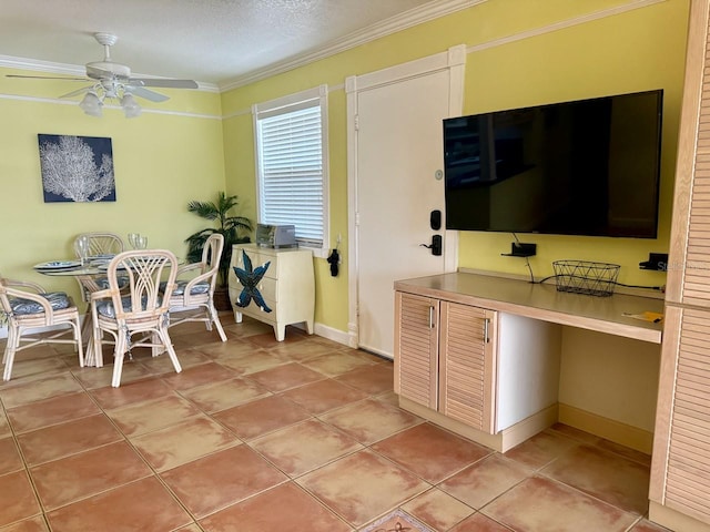 dining area with ceiling fan, a textured ceiling, light tile patterned floors, built in desk, and ornamental molding