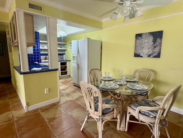 tiled dining room with ceiling fan and crown molding