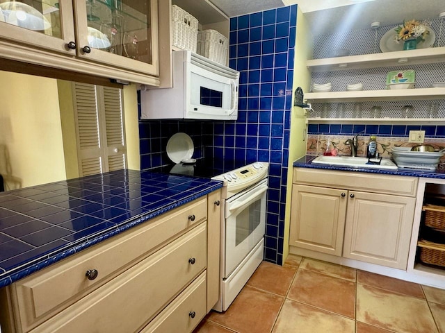 kitchen with tasteful backsplash, white appliances, sink, light tile patterned floors, and tile countertops