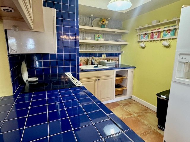 interior space featuring decorative backsplash, tile patterned floors, sink, tile countertops, and white fridge with ice dispenser