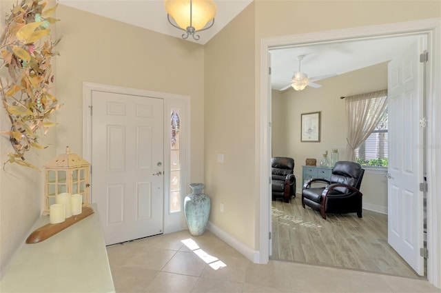 entrance foyer featuring ceiling fan, light tile patterned flooring, and vaulted ceiling