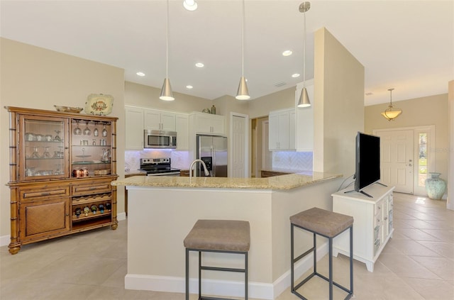 kitchen featuring white cabinetry, kitchen peninsula, a breakfast bar area, decorative backsplash, and appliances with stainless steel finishes