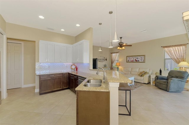 kitchen with backsplash, sink, pendant lighting, white cabinets, and a breakfast bar area