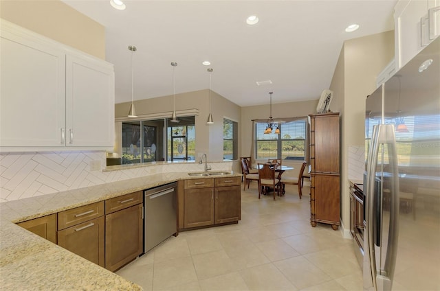 kitchen with light stone countertops, sink, backsplash, pendant lighting, and appliances with stainless steel finishes