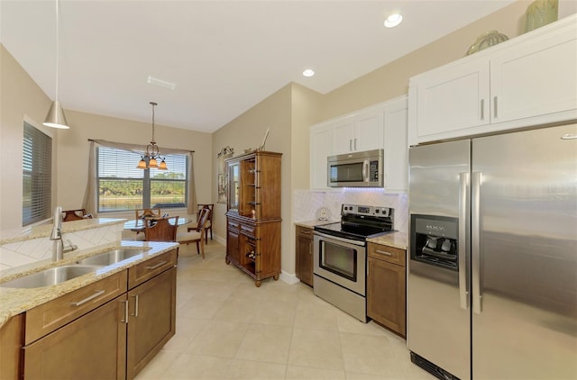 kitchen featuring sink, appliances with stainless steel finishes, decorative light fixtures, white cabinetry, and a chandelier