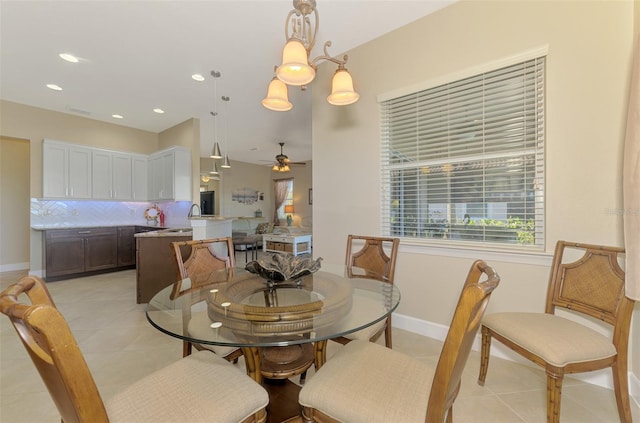 tiled dining space featuring sink and ceiling fan with notable chandelier