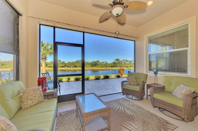 sunroom featuring ceiling fan and a water view