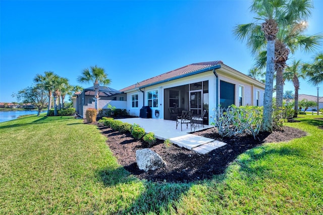 back of property with a lawn, a sunroom, a patio area, and a water view