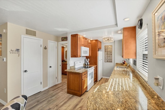 kitchen with white appliances, light hardwood / wood-style floors, light stone counters, and sink