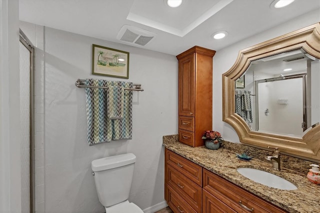 bathroom featuring vanity, a tray ceiling, toilet, and a shower with door