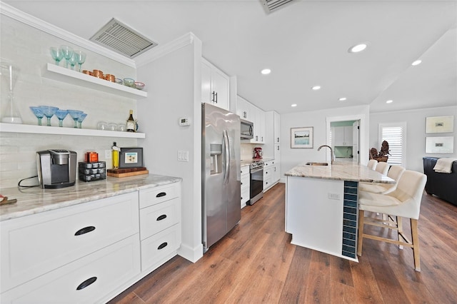 kitchen featuring sink, stainless steel appliances, light stone counters, an island with sink, and a breakfast bar area