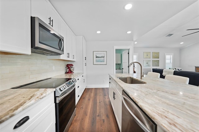 kitchen with light stone countertops, appliances with stainless steel finishes, white cabinetry, and sink