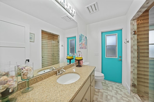 bathroom featuring vanity, a shower with shower door, and toilet