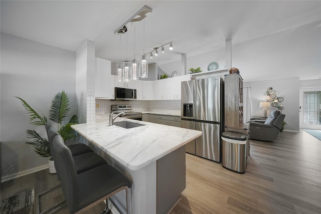 kitchen featuring white cabinets, a kitchen breakfast bar, decorative light fixtures, kitchen peninsula, and stainless steel appliances