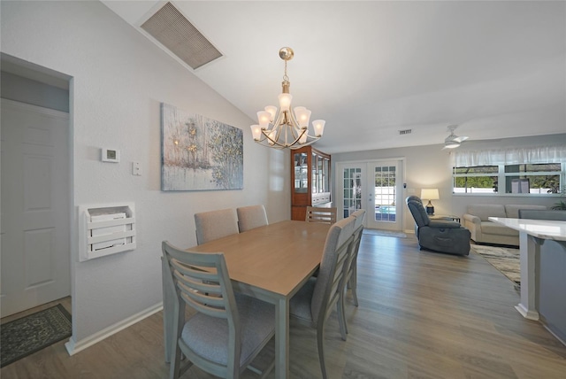 dining space featuring lofted ceiling, french doors, dark wood-type flooring, and ceiling fan with notable chandelier