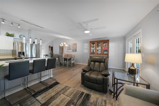 living room featuring hardwood / wood-style flooring, ceiling fan with notable chandelier, sink, and rail lighting