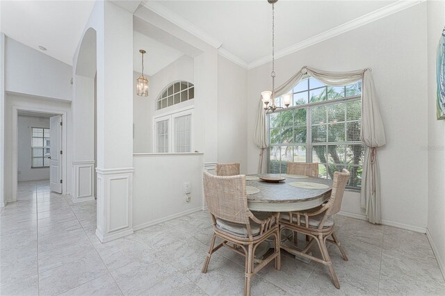 dining space featuring lofted ceiling, ornamental molding, and a notable chandelier