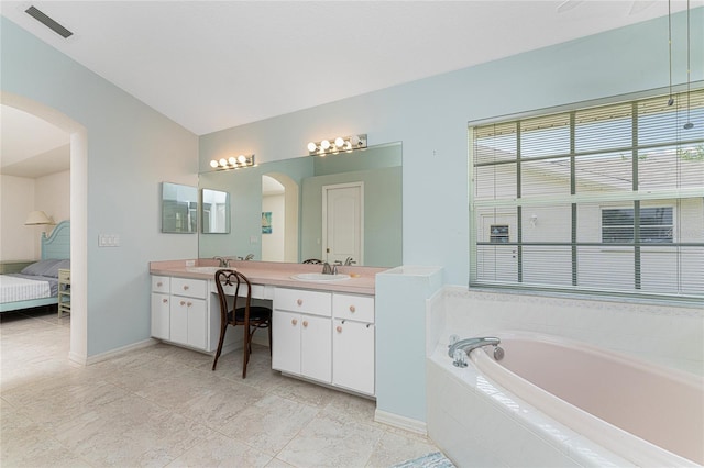 bathroom featuring a relaxing tiled tub, vanity, a healthy amount of sunlight, and tile patterned flooring