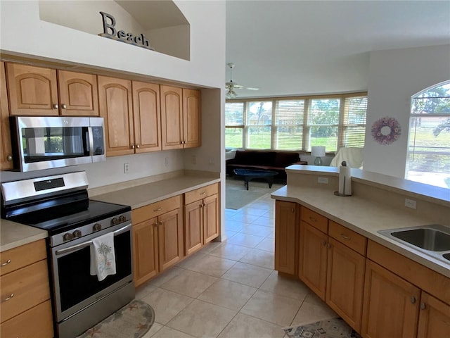 kitchen with light tile patterned floors, stainless steel appliances, light countertops, and a ceiling fan