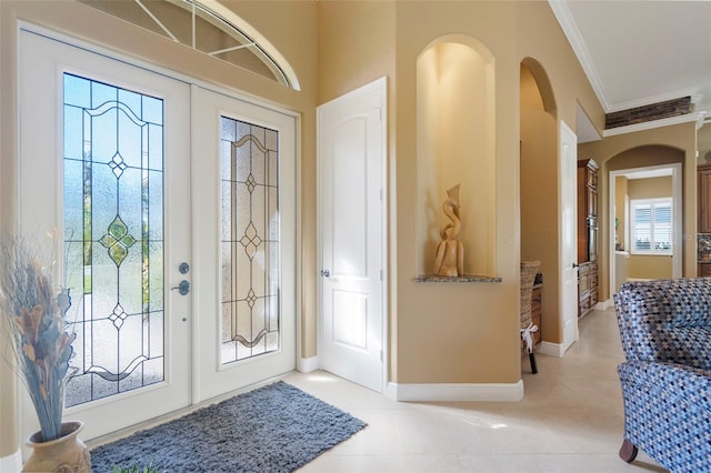 tiled entrance foyer with ornamental molding and french doors