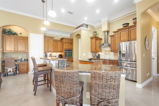 kitchen featuring wall chimney exhaust hood, pendant lighting, a breakfast bar, a kitchen island, and appliances with stainless steel finishes