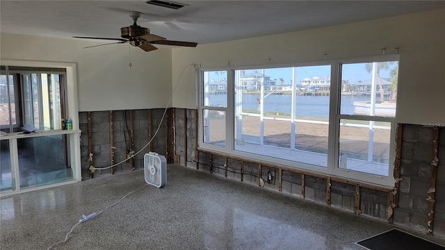 unfurnished room with ceiling fan and a water view