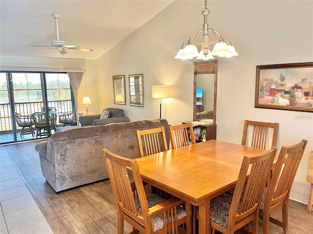 dining space with light hardwood / wood-style flooring, ceiling fan with notable chandelier, and lofted ceiling