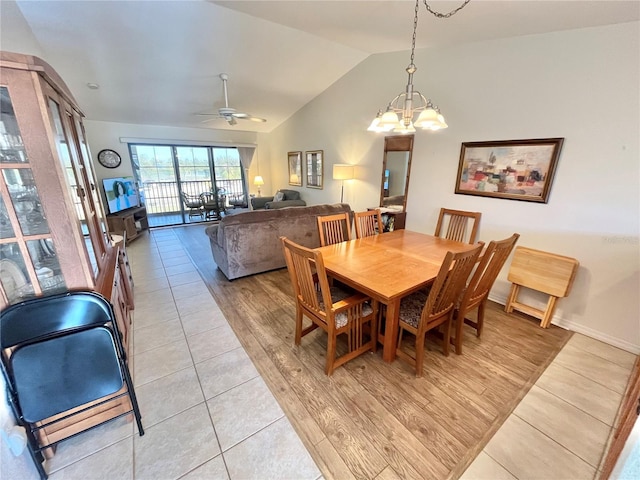 dining space featuring ceiling fan with notable chandelier, light wood-type flooring, and vaulted ceiling