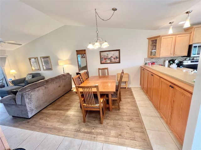 dining area featuring ceiling fan with notable chandelier, light hardwood / wood-style floors, and lofted ceiling